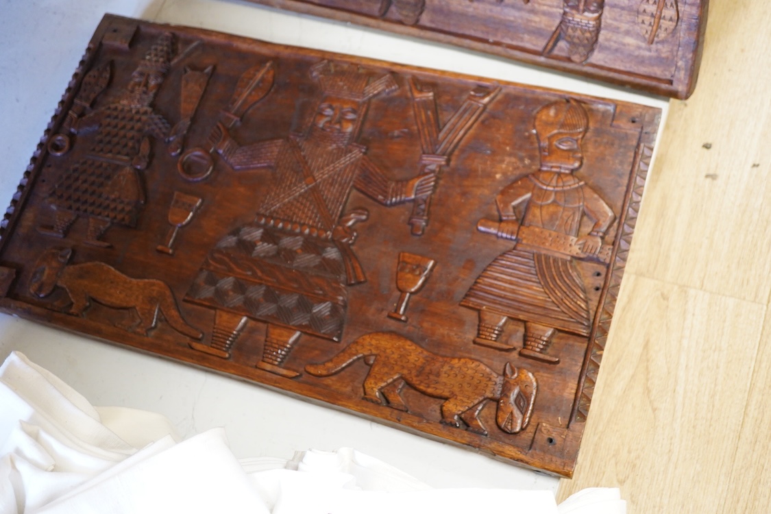 A set of three African carved figurative wooden panels, 64.5cm wide x 37cm high